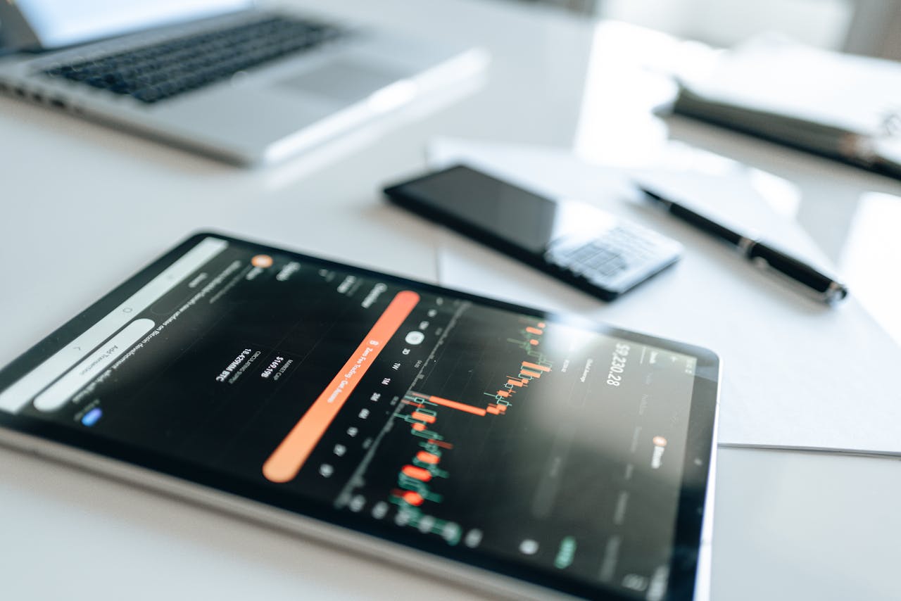 Modern financial tools including tablet with market trends on white desk setup.
